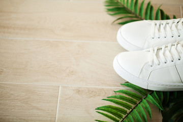 Pair of new stylish white sneakers on wood floor.