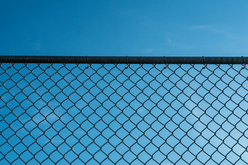 background of metal fence under clear blue sky on a sunny day