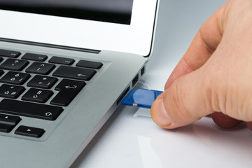 Mans hand inserting the sd memory card into the laptop slot. Copy information from the memory card...