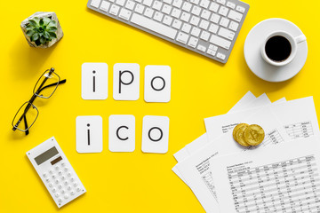 Initial Coin Offering, Initial Public Offering with coins, calculation tables, office tools yellow background top view