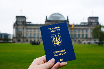 Ukrainian passport in front of Bundestag building in Berlin, Germany. Travel concept