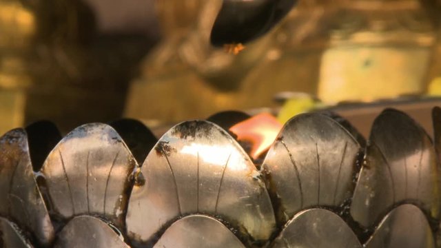 A steady, extreme close up shot of a beautiful red flame burning in a silver bowl. 