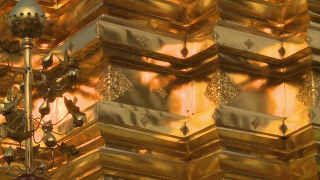 A steady, medium shot of golden decorations on the walls of a tall temple.