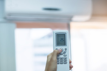 hand using remote controller for adjust Air conditioner inside the room of office or house