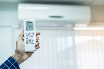 hand using remote controller for adjust Air conditioner inside the room of office or house