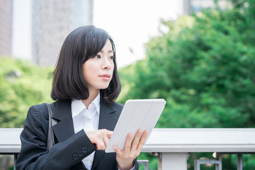 Young business woman using tablet computer outside