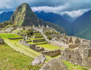 A close-up view of the ruins and vibrant green terraces at the base of Huayna Picchu mountain in beautiful Machu Picchu, Peru.