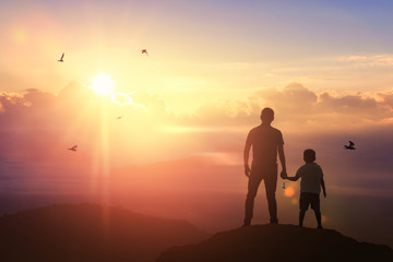 Father and son holding hand in hand on background sunset. Father holiday