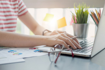 Close up of women or accountant hand holding pen working on calculator to calculate financial data report, accountancy document and laptop computer at office, business concept