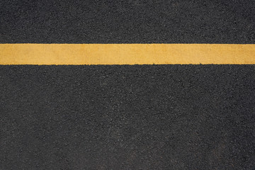 A parallel yellow paint line close-up text space on black asphalt road