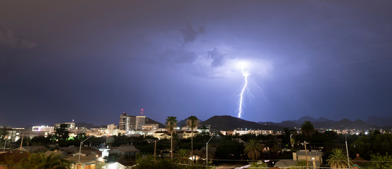 Purple Blue light illuminates the sky over the buildings homes and hills around Tucson Arizona