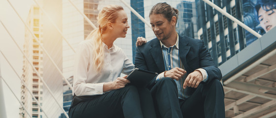 caucasian business partners having business discussion outdoors with tablet on hand