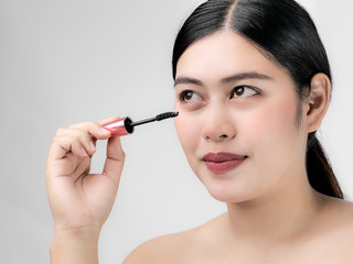 Close-up portrait of nice lovely cute sweet attractive  cheerful positive Asian woman holding in hands applying trendy black mascara isolated over gray background.