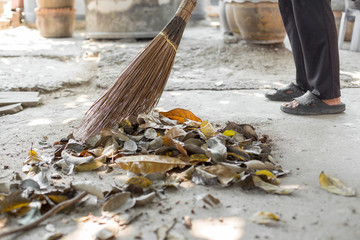 People are sweeping the leaves on the concrete floor