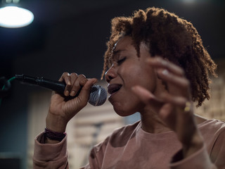 close up side view of one young african singer singing on the stage