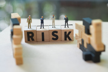 Miniature people businessmen stand on cube word with risk. Risk analysis for investment