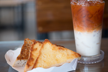 Garlic bread in white paper tray served with Thai milk tea
