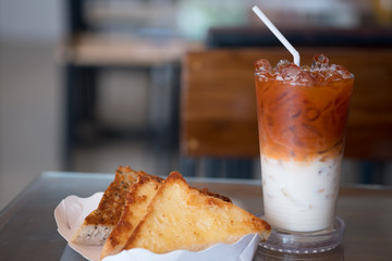 Garlic bread in white paper tray served with Thai milk tea