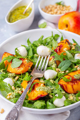 Salad with arugula, nectarines and pesto sauce.