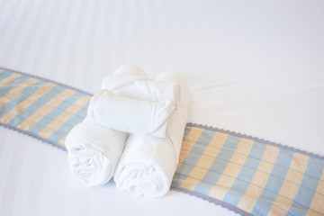 Set of white towels on the bed, towels rolled on the bed in hotel, amenity and accommodation in hotel and tourist concept.