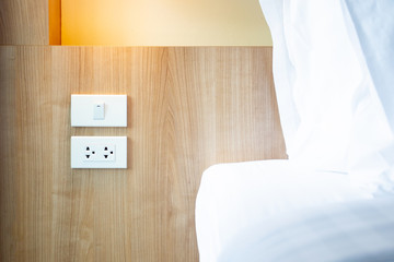 Modern electric plug socket and electric switch beside the boardhead (bed) close up. - obrazy, fototapety, plakaty