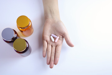 Three color capsules in the hand and a medicine bottle.