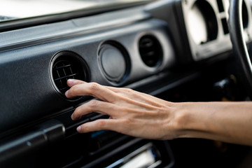 Man adjusting vehicle air conditioner grill on the front dashboard console close up.  Concept of safe driving and automobile care.