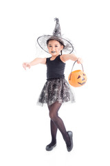 Full length of little asian girl in witch costume standing and holding halloween pumpkin bucket over white background