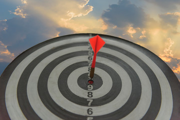 The red arrow dashed towards the center of the dartboard, sunset background. Set business goals, achieving and winning concepts.
