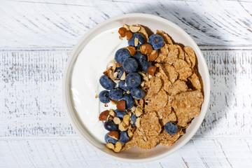 bowl of healthy wholegrain flakes, yogurt and blueberries, top view