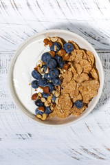 bowl of healthy wholegrain flakes, yogurt and blueberries, vertical closeup
