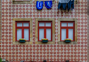Traditional house facade decorated with ornate Portuguese azulejo tiles and laundry hanging outside in Porto, Portugal
