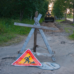 Road repair work - a yellow tractor stands on the sidewalk, which will repair. In the foreground is...