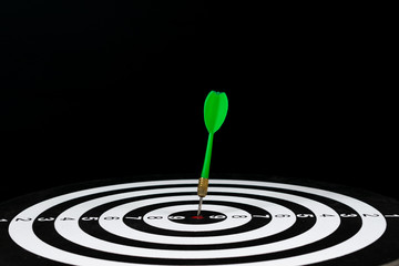 Fototapeta na wymiar Green dart arrow hitting in the target center of dartboard with copy space for text. Marketing concept.