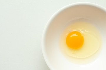 Fresh raw egg in bowl on white background.