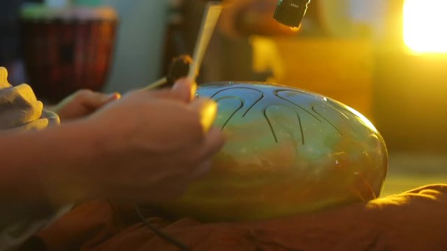 musician plays sticks on musical instrument hapi drum in music lesson