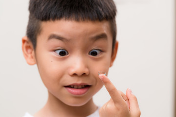 Asian boy look at contact lens