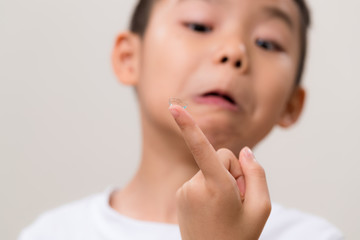 Asian boy look at contact lens