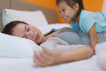 Sleepy mother trying to rest with her child in bed.