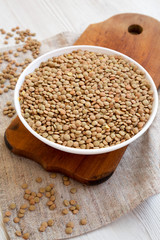 Organic green lentils in a white bowl on a rustic wooden board, low angle view. Close-up.