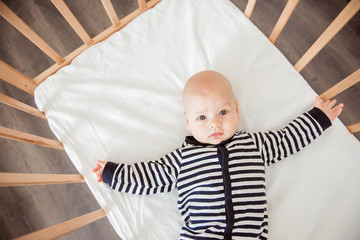 Newborn baby lying in bed in striped clothes