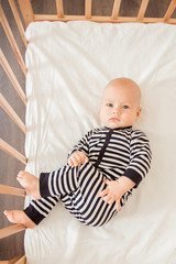 Newborn baby lying in bed in striped clothes