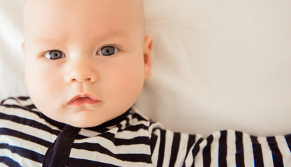Newborn baby lying in bed in striped clothes