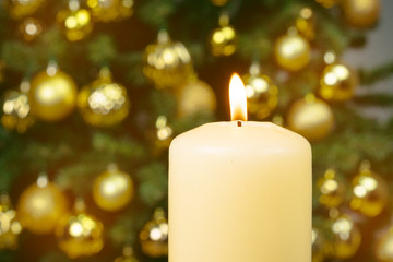 Obraz na płótnie Canvas Lit christmas candle against decorated fur tree background