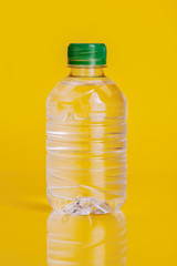 Plastic bottle of mineral water on a bright yellow background