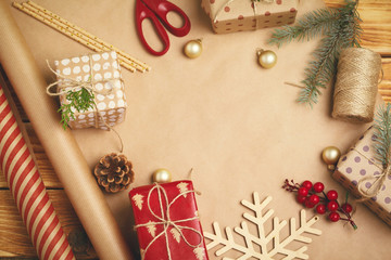 Fototapeta na wymiar Christmas festive mood. Flat-lay of decorations, ribbons, gift paper, wrapped gift on wooden background