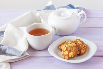 Cup of tea with cookies over lilac wooden background