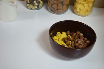 Breakfast cereal, chocolate balls in a brown bowl. Healthy breakfast. Diet Bowl and spoon with corn flakes isolated on white background