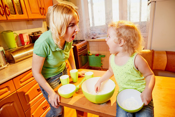 Mother and her three years old blonde daughter are arguing and swearing in the kitchen during...