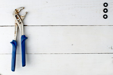 old adjustable wrench and black rubber gasket on the white wooden table